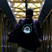 Black guy wearing leather jacket opened up to show cool astronaut LED t-shirt with equalizer lighting up