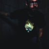 White guy with glasses crouching in dark stairwell wearing Flaming Skull LED T-shirt design lighting up in the dark