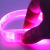 Someone's hand pressing button on pink LED bracelet
