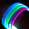 Close up image of clear LED bracelets when turned on, blue, green, and pink LED bracelets on wrist