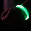 Green LED bracelet lighting up on person's wrist with hand in a fist