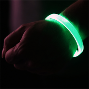 Green LED bracelet lighting up on person's wrist with hand in a fist