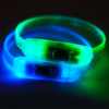 Close up image of two led bracelets with button battery lighting up in blue and green
