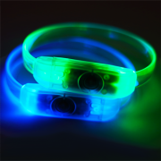 Close up image of two led bracelets with button battery lighting up in blue and green