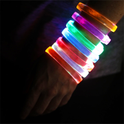 Someone wearing 7 different LED bracelets on their arm, all lighting up in different colors