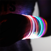 Extra close up of Someone wearing 7 different LED bracelets on their arm, all lighting up in different colors