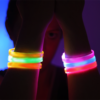 Girl in dark room holding up arms in front of face to show LED bracelets on wrist lighting up in many different colors
