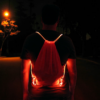 Guy wearing red LED drawstring bag in middle of street at night