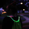 Girl wearing green LED drawstring bag at night in neighborhood