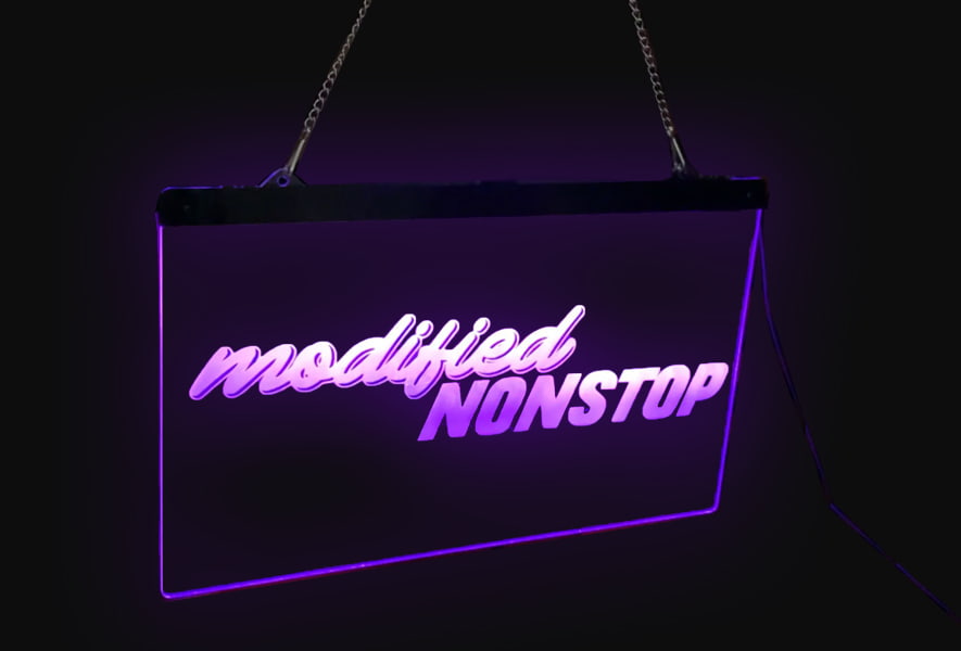 Acrylic etched LED sign reading "modded stop", hanging on a chain against a dark background