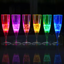 6 pack of LED champagne flutes in a line glowing bright red, pink, orange, yellow, green, and blue in a dark room