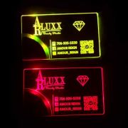 Two business cards for Beauty Salon with company logo, contact information and QR code lighting up brightly in dark room. Top business card is bright yellow and bottom business card is bright red. Same business card different LED lights in dark room