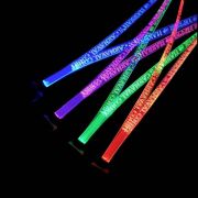 Carnival logo laser engraved onto bright neon LED lanyards shining red, green, purple and blue on four different lanyards in a dark room