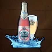 Poster Of Castel Beer bottle and glass with splash effect lighting up brightly in dark setting