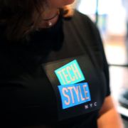 Close up of woman wearing tightly fitted light up shirt with Tech Style logo illuminating brightly