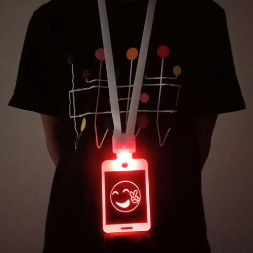 Close up of person wearing LED badge around neck that is glowing bright red with a smiley face logo