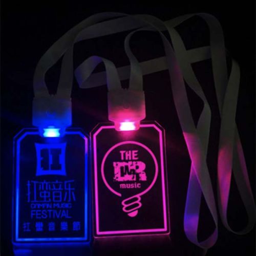 Two custom LED badges on nylon lanyards side by side, badge on left is lighting music festival logo in bright blue and badge on right is lighting a music logo in hot pink