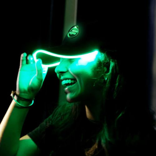 Smiling woman wearing Green LED baseball hat that is lighting up her face