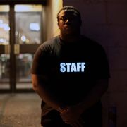 Man standing in front of venue wearing bright shining Staff LED t-shirt