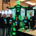 Group of five people wearing custom LED shirts standing with man in full LED Tron suit