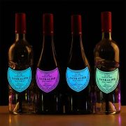 Four wine bottles in a row each with their own brightly lit up neon EL panel label