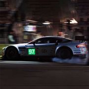 Racer driving at night with smoking tires in the back and bright neon EL sign on the car illuminating the number 97 in lime green and white