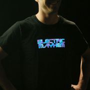 Smiling guy with hands on hips sporting a light up shirt with the words "Electric Mayhem" illuminating