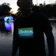 Man wearing Flashion Statement custom LED t-shirt outside with Christmas lights in the background