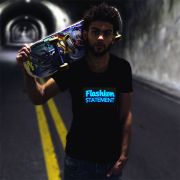 Man holding skateboard over their shoulder walking through dark tunnel with custom Flashion Statement light up shirt shining brightly