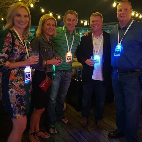 Group of five professional adults at networking event wearing LED ID badges with their names lighting up