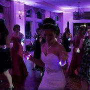 Bride dancing at wedding with two different LED bracelets on each wrist while other guests re dancing with custom led bracelets shining bright on their arms