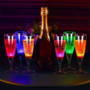 Champagne bottle on a table surrounded by three LED champagne glasses on each side each lighting up a different color