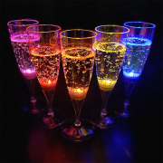Five different color LED Champagne flutes in a V pattern brightly glowing in dark room