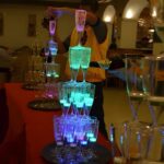 LED champagne glasses stacked into a tower glowing bright neon blue and green at wedding