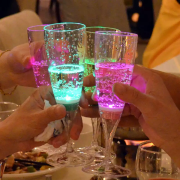 a group of four LED champagne glasses in a cheers position lighting up bright green and pink