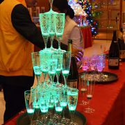 Three tiers of LED champagne glasses stacked up high on a table illuminating bright green