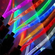 Close up on laser engraved logos and text on custom LED lanyards, each one glowing a different bright color: pink, orange, green, blue, yellow, red, white and blue again