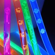 Close up image of four LED lanyards with laser engraved logos and text lighting up brightly in neon pink, orange, green and blue