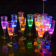14 different LED champagne glasses on dark bar top glowing bright neon colors