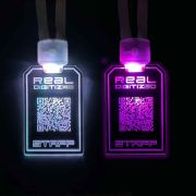 Two light up badges lighting up in white and pink for staff to wear at an event