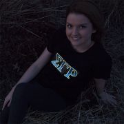 Smiling girl posing in dark while sorority greek letters are lighting up on her shirt
