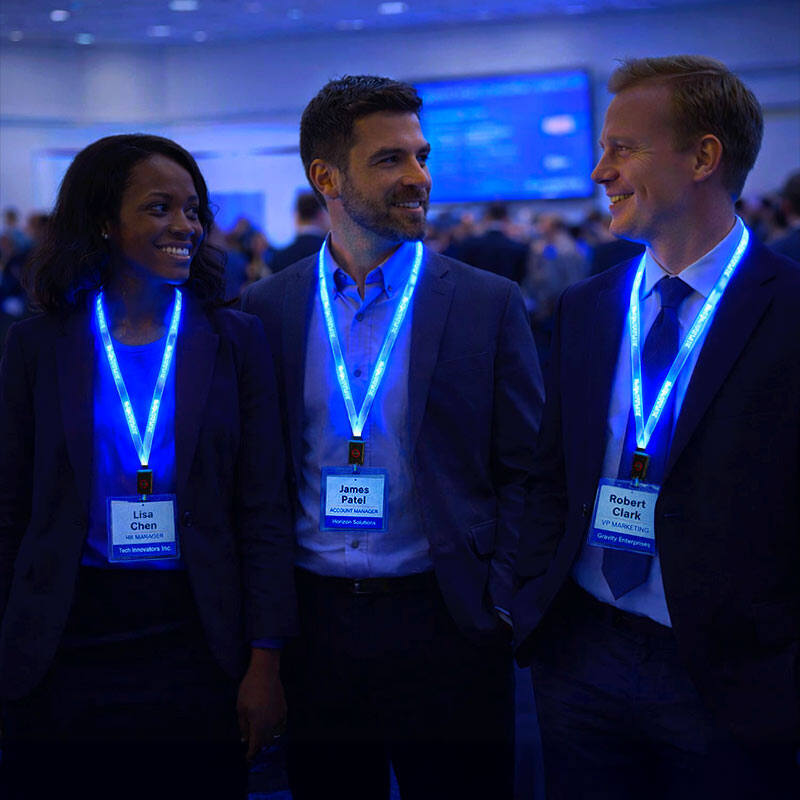 Three professionals at a conference wearing blue LED light-up lanyards while smiling and interacting in a dimly lit event setting