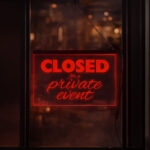 Red LED edge-lit hanging sign reading 'Closed for a private event' glowing in a window