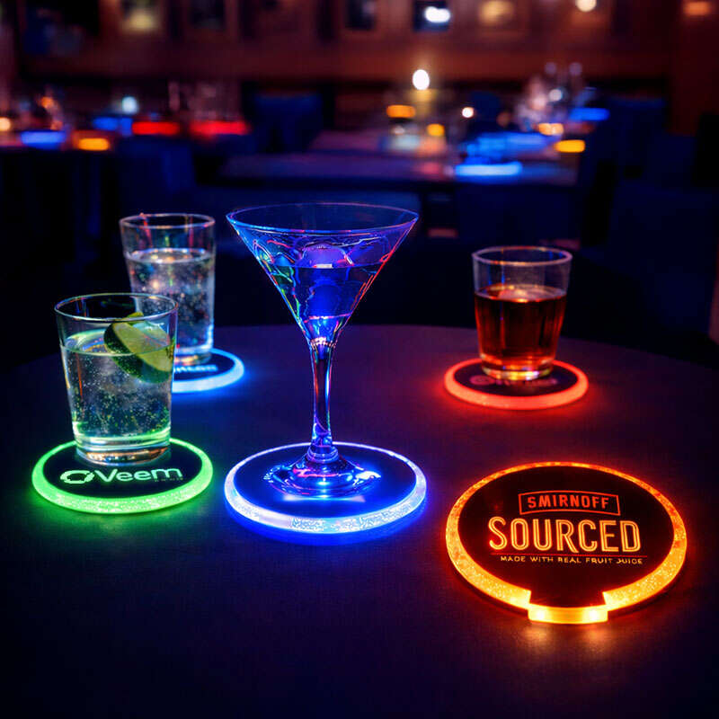Illuminated custom logo coasters placed under drinks on a party table with vibrant lighting