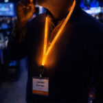 Detailed view of an orange light-up lanyard worn at a tech-style gathering