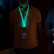 Two men sporting illuminated, branded lanyards that glow in the dark, enhancing their appearance in a low-light environment