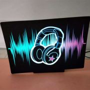 headphones sound wave equalizer design lighting up bright neon color on el panel in brightly lit room