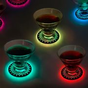 Four glasses on light-up coasters, glowing in green, red, and yellow LED lights