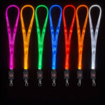 Row of brightly illuminated LED lanyards in multiple colors arranged against a black background