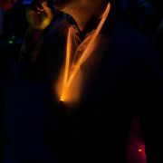A side view of a man in the dark, wearing a bright orange LED lanyard that emits a glowing light